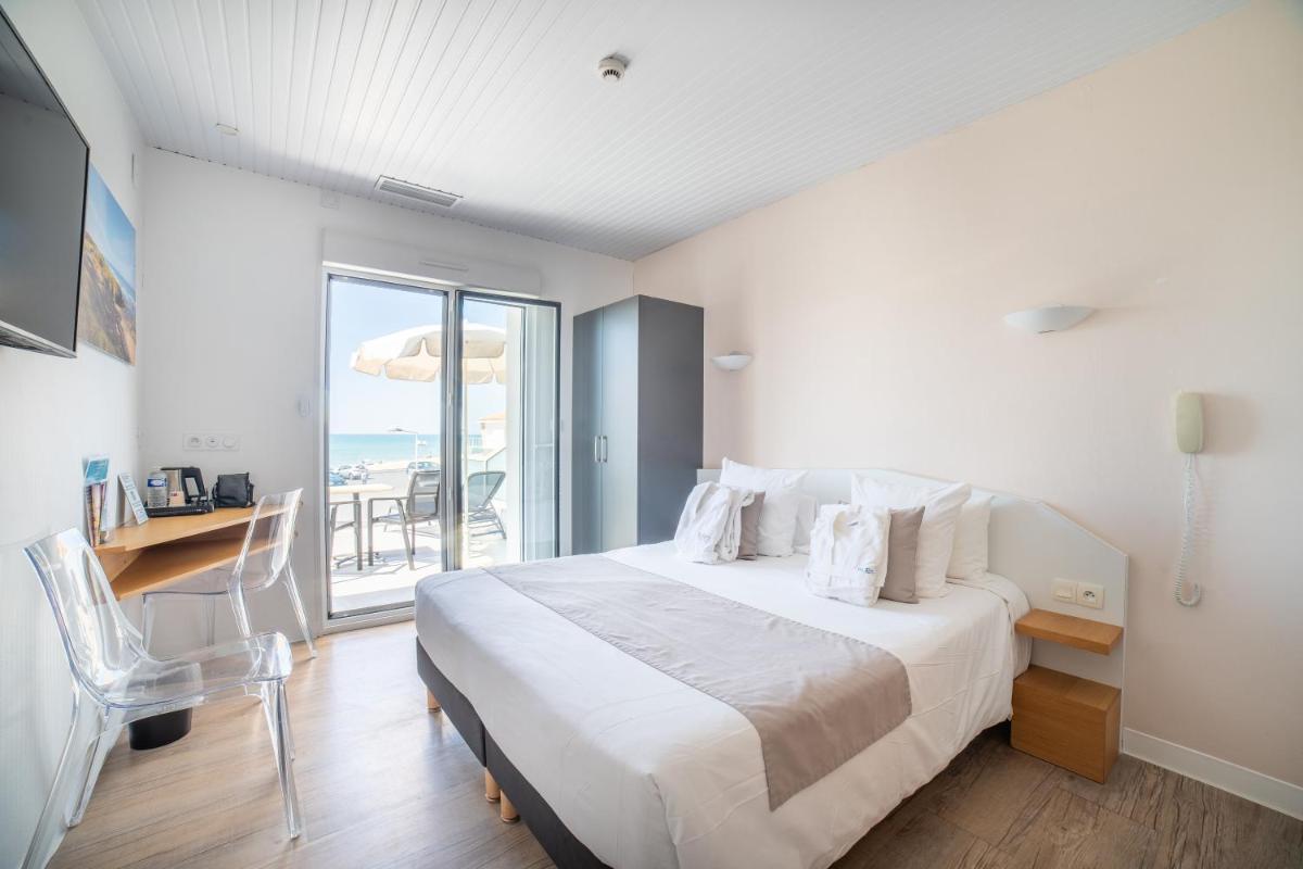 une chambre avec un lit, un bureau et une fenêtre dans l'établissement Hotel Les Dunes, à La Tranche-sur-Mer