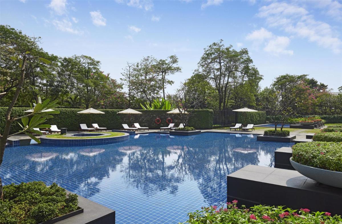 a swimming pool with chairs and umbrellas at Grand Hyatt Mumbai Hotel and Residences in Mumbai