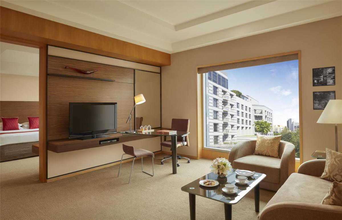 a living room with a large window and a television at Grand Hyatt Mumbai Hotel and Residences in Mumbai