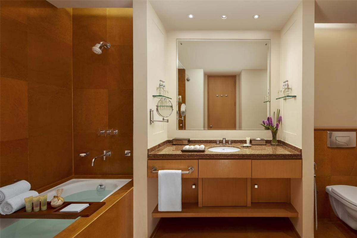 a bathroom with a tub and a sink and a mirror at Grand Hyatt Mumbai Hotel and Residences in Mumbai