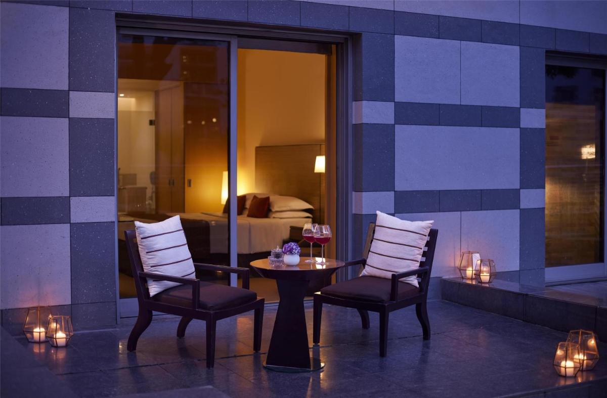 a room with two chairs and a table and a bedroom at Grand Hyatt Mumbai Hotel and Residences in Mumbai