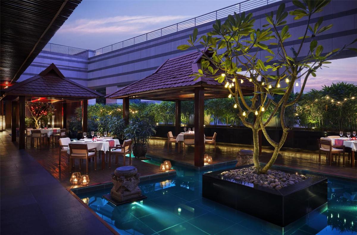 a restaurant with a tree in the middle of a pool at Grand Hyatt Mumbai Hotel and Residences in Mumbai