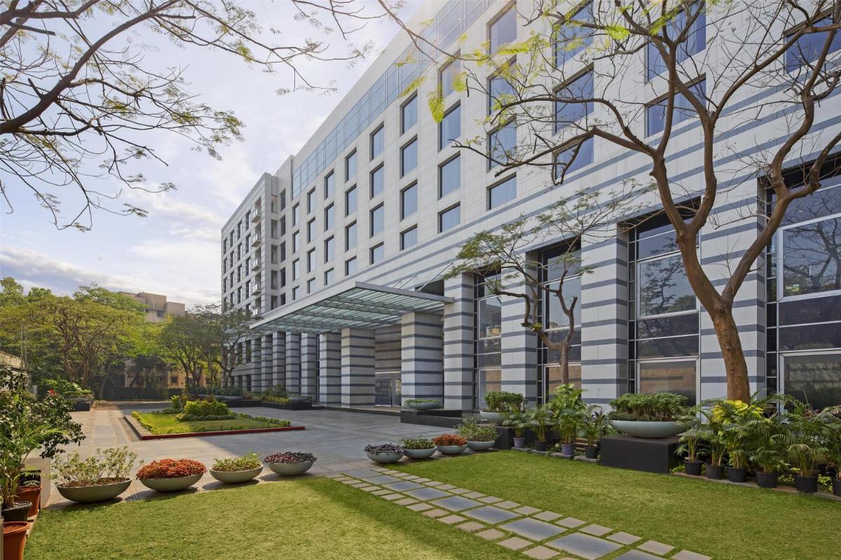 a building with a garden in front of it at Grand Hyatt Mumbai Hotel and Residences in Mumbai