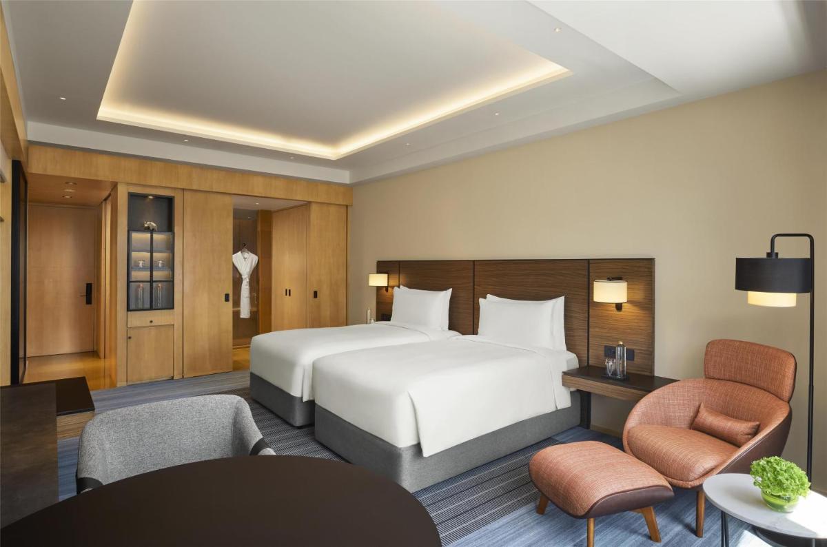 a hotel room with a bed and a table and chairs at Grand Hyatt Mumbai Hotel and Residences in Mumbai