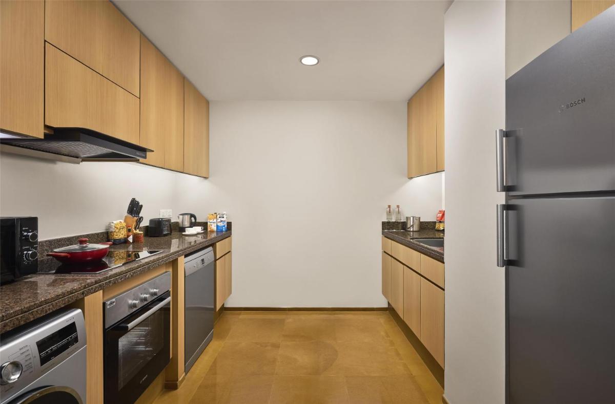 a kitchen with stainless steel appliances and wooden cabinets at Grand Hyatt Mumbai Hotel and Residences in Mumbai