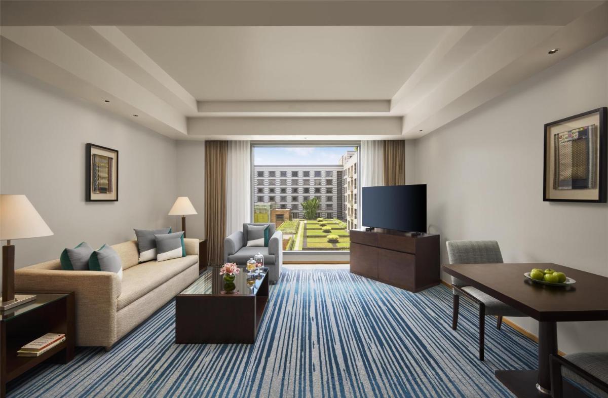 a living room with a couch and a tv at Grand Hyatt Mumbai Hotel and Residences in Mumbai