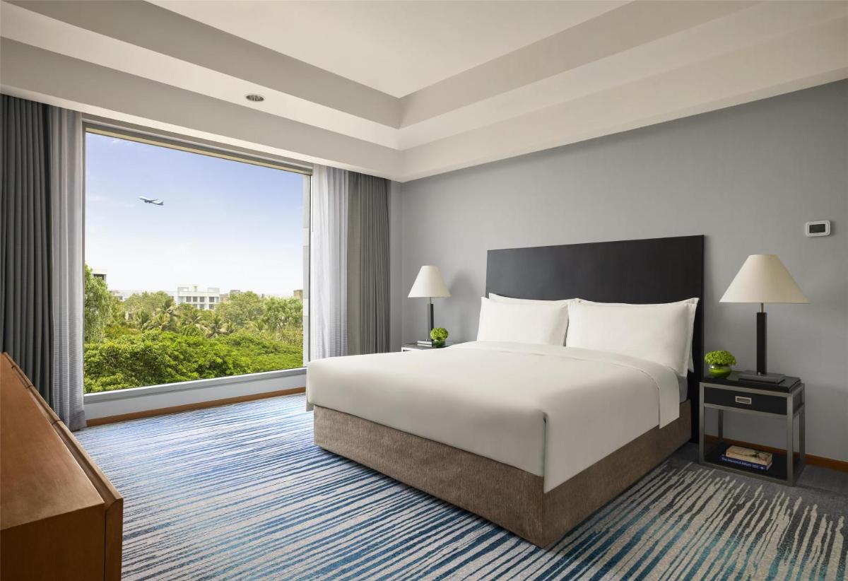 a hotel room with a bed and a large window at Grand Hyatt Mumbai Hotel and Residences in Mumbai