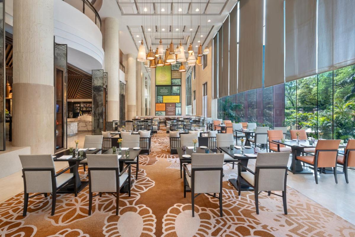 a dining area with tables and chairs in a restaurant at Sheraton New Delhi Hotel in New Delhi a dining area with tables and chairs in a restaurant at Sheraton New Delhi Hotel in New Delhi