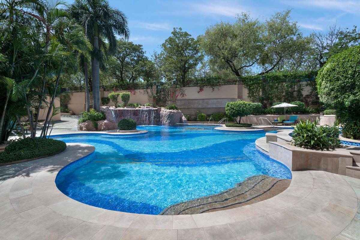 a swimming pool with blue water in a yard at Sheraton New Delhi Hotel in New Delhi