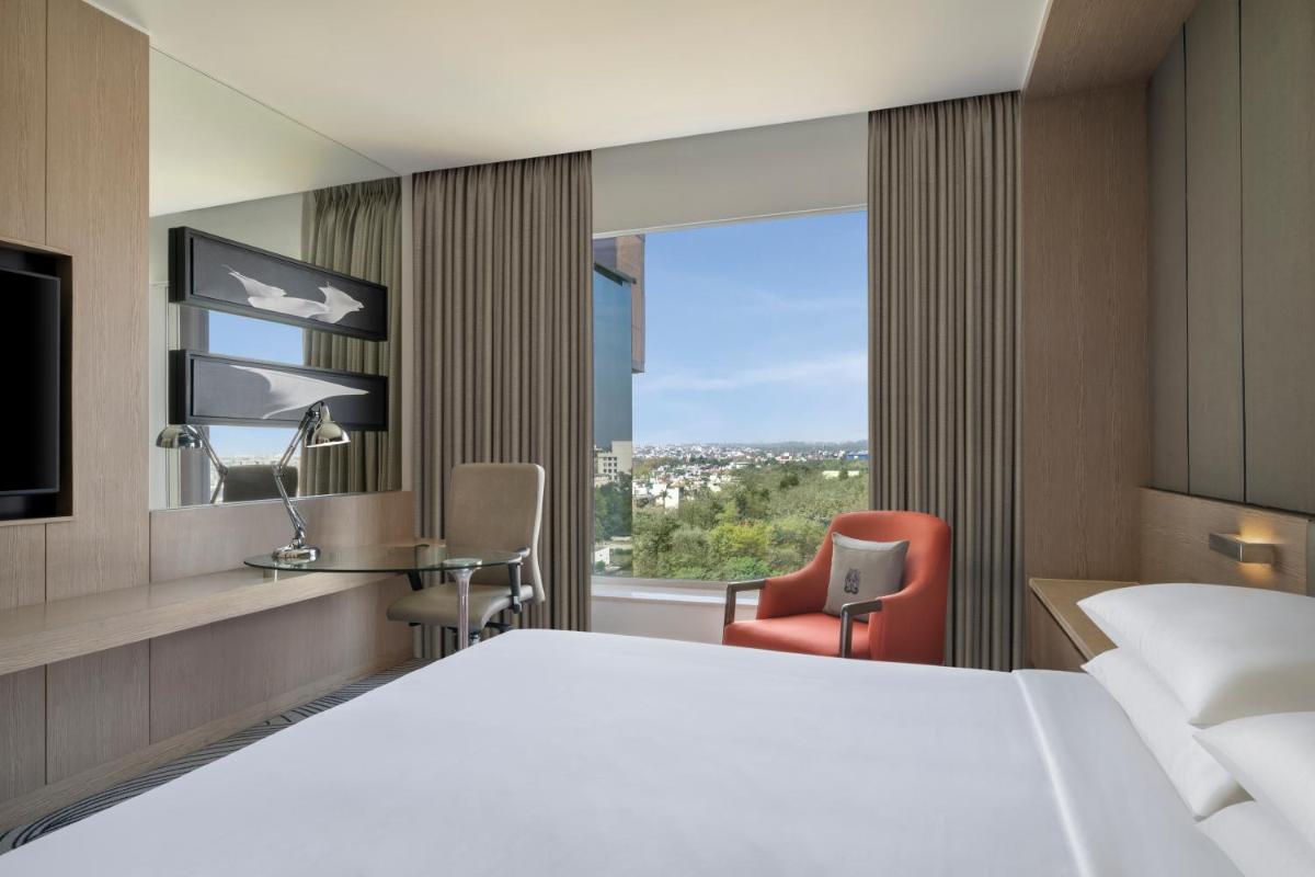 a hotel room with a large white bed and a window at Sheraton New Delhi Hotel in New Delhi a hotel room with a large white bed and a window at Sheraton New Delhi Hotel in New Delhi