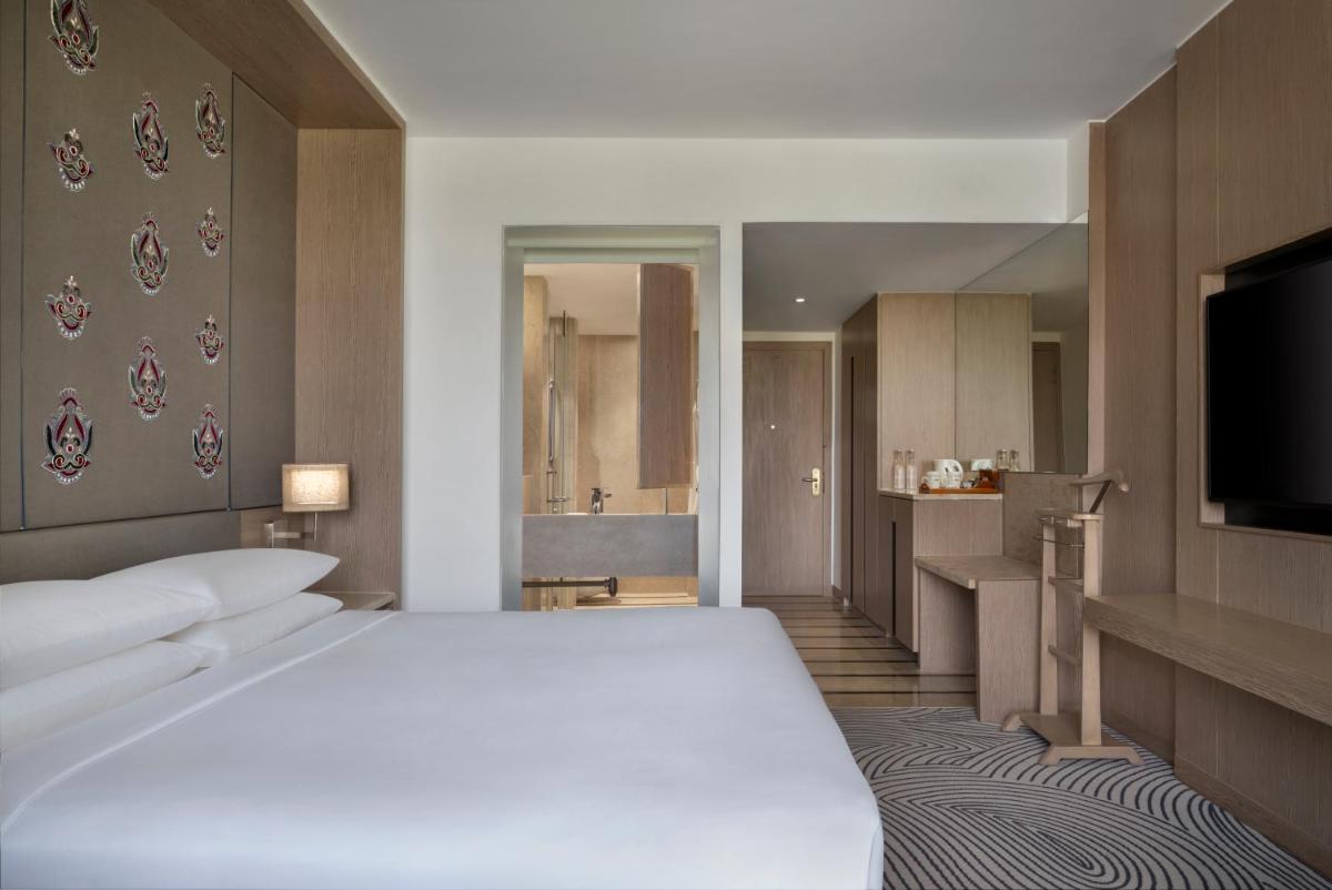 a bedroom with a large white bed and a kitchen at Sheraton New Delhi Hotel in New Delhi a bedroom with a large white bed and a kitchen at Sheraton New Delhi Hotel in New Delhi