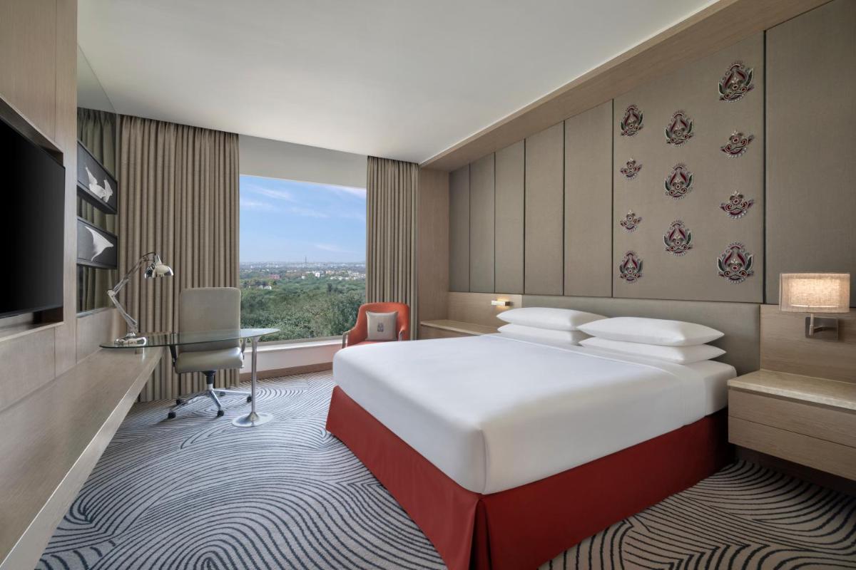 a hotel room with a large bed and a desk at Sheraton New Delhi Hotel in New Delhi a hotel room with a large bed and a desk at Sheraton New Delhi Hotel in New Delhi