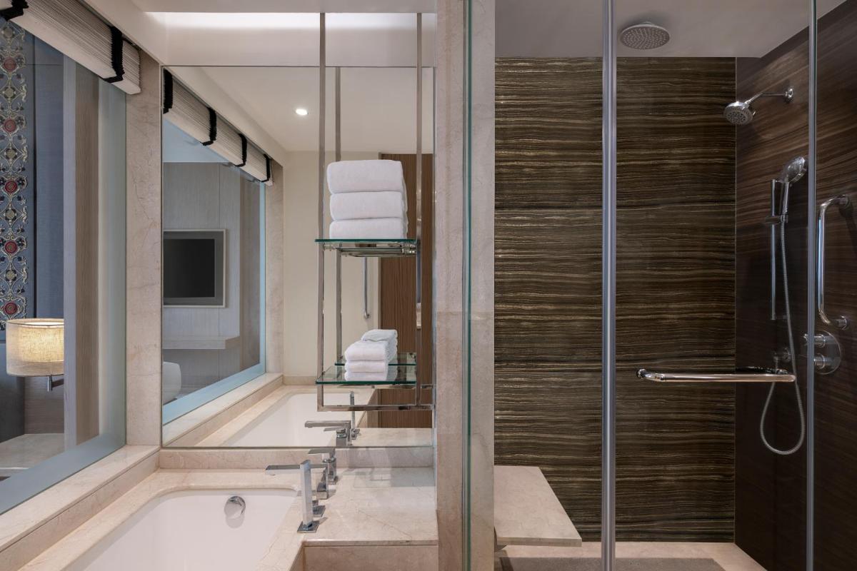 a bathroom with a tub and a shower with a glass door at Sheraton New Delhi Hotel in New Delhi