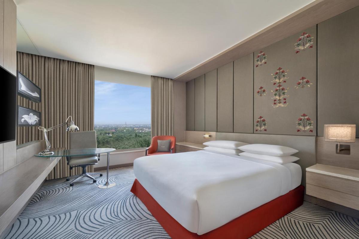 a hotel room with a large bed and a desk at Sheraton New Delhi Hotel in New Delhi a hotel room with a large bed and a desk at Sheraton New Delhi Hotel in New Delhi