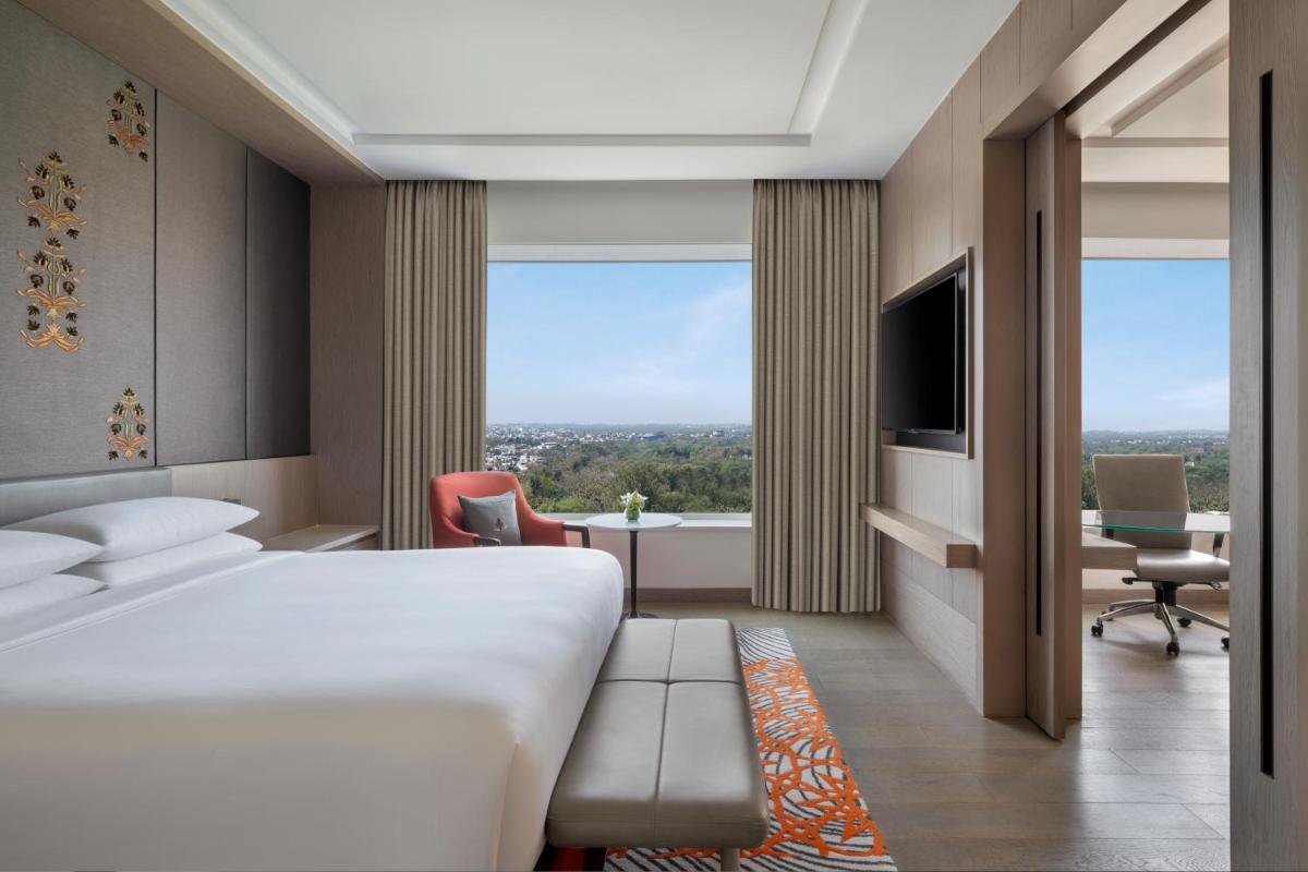 a hotel room with a large bed and a desk at Sheraton New Delhi Hotel in New Delhi a hotel room with a large bed and a desk at Sheraton New Delhi Hotel in New Delhi