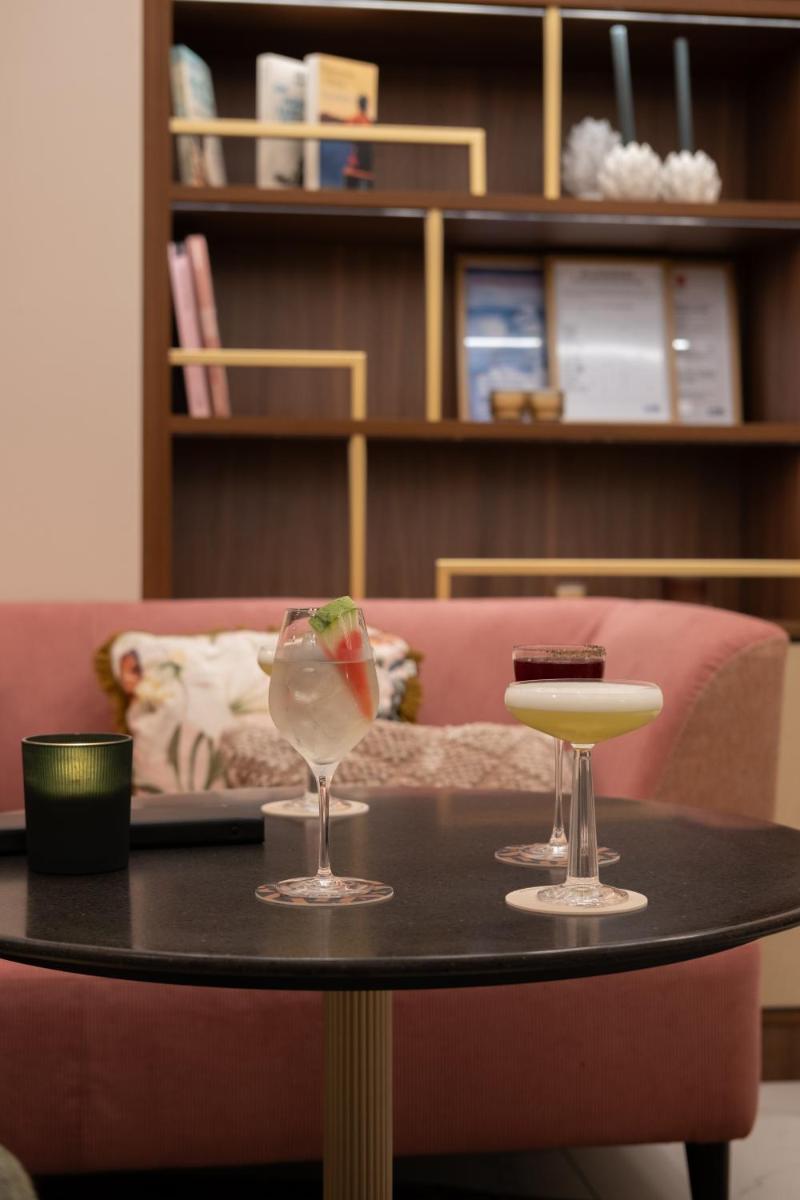 une table avec deux verres à vin et un canapé dans l'établissement Hotel & Spa Oceania Lille Les Augustins, à Lille