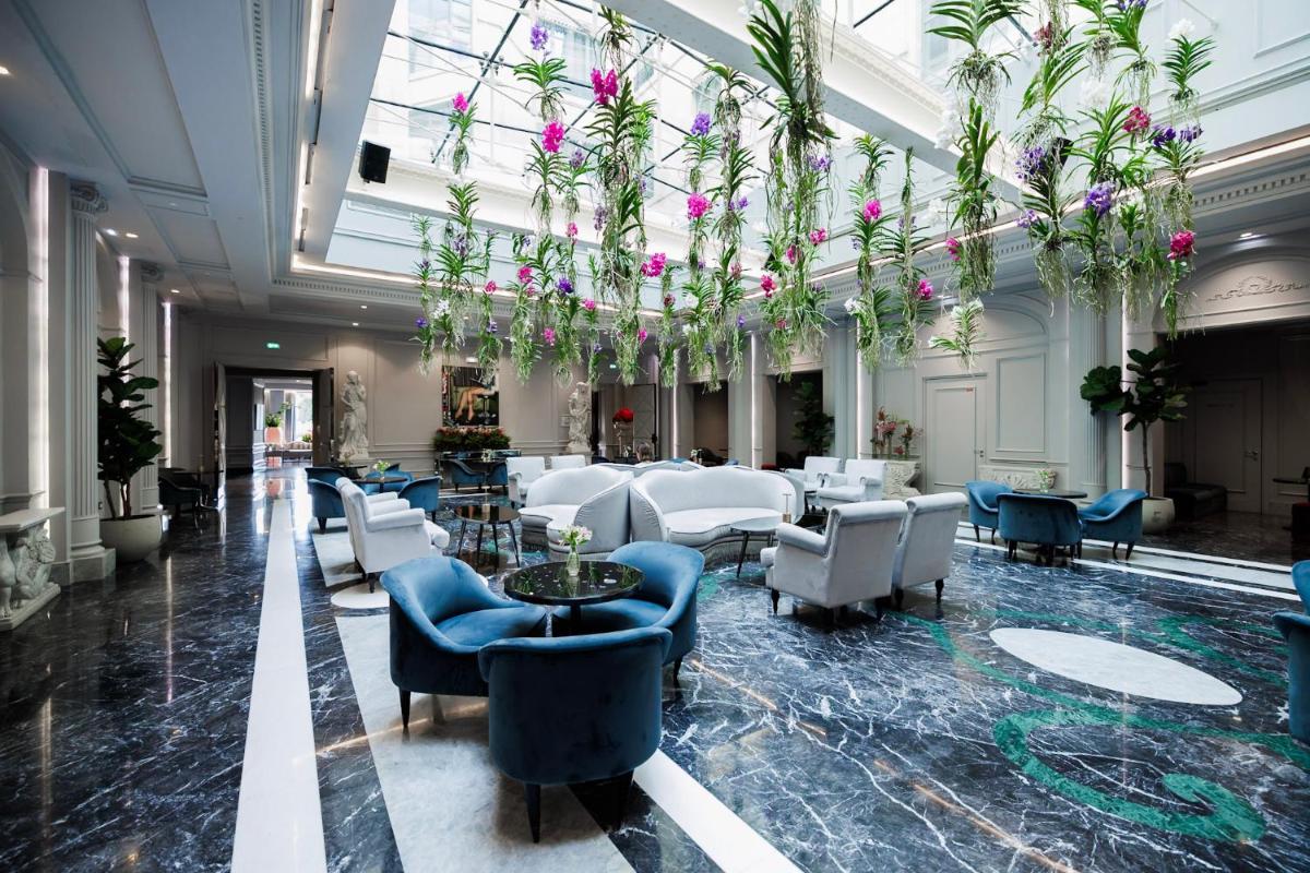 un hall avec des chaises bleues et des fleurs suspendues au plafond dans l'établissement Boscolo Lyon Hotel & Spa, à Lyon
