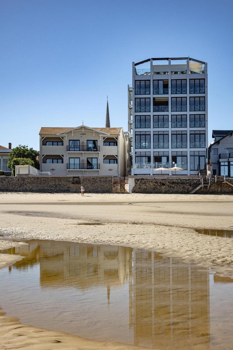 un bâtiment sur la plage avec un reflet dans le sable dans l'établissement Les Vagues Hotel & Spa, à Arcachon