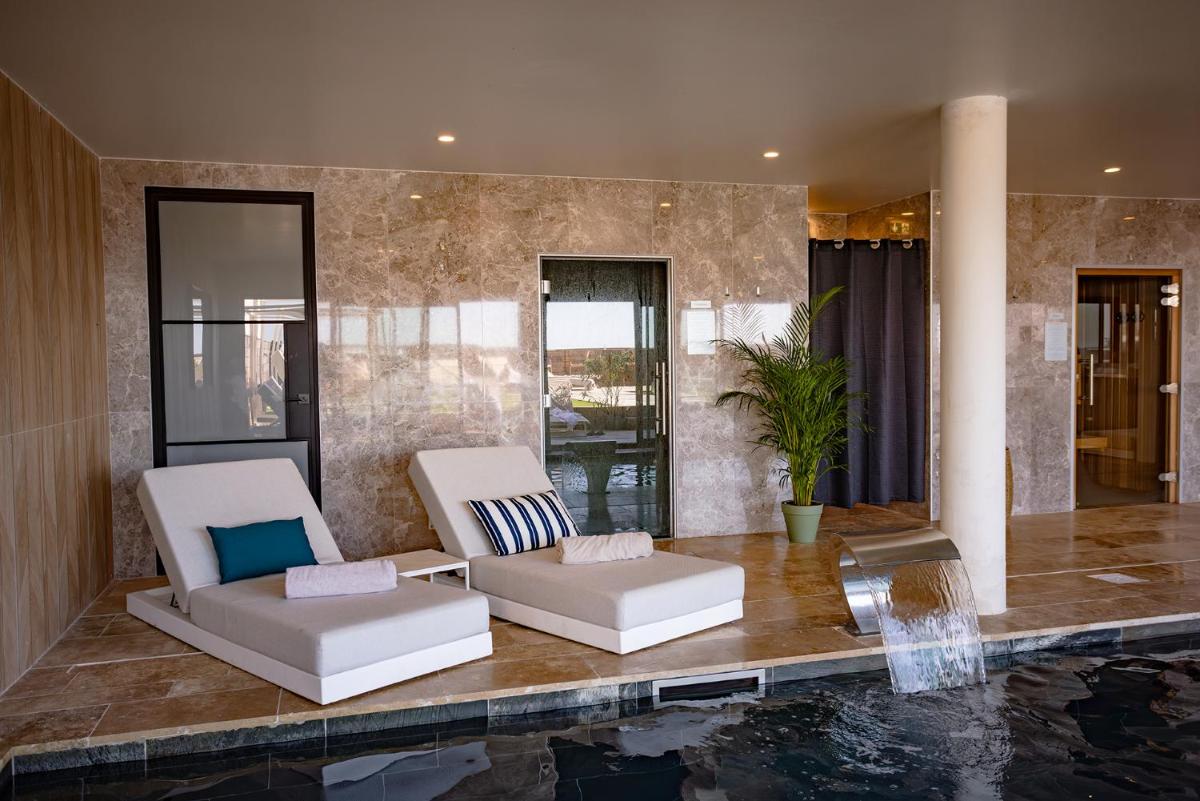 - un salon avec deux chaises et une piscine dans l'établissement Les Vagues Hotel & Spa, à Arcachon