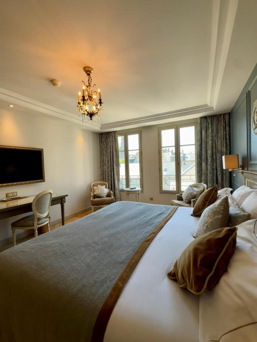 - une grande chambre avec un grand lit et un lustre dans l'établissement Villa Lara Hotel, à Bayeux
