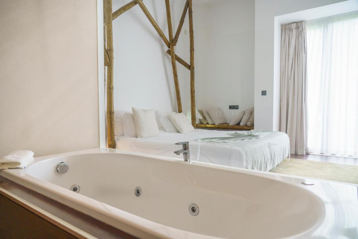 uma banheira branca em um quarto com uma cama em Real Abadia, Congress & Spa Hotel em Alcobaça