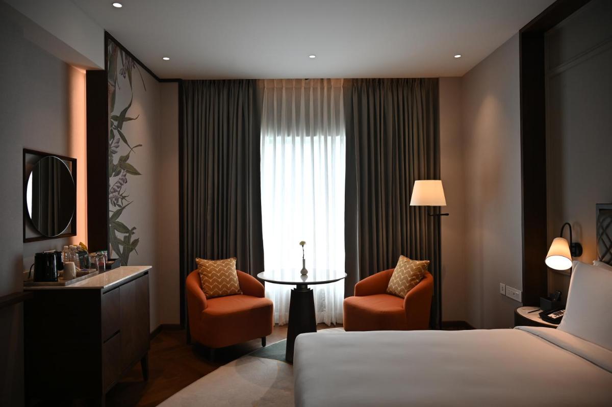 a hotel room with a bed and two chairs and a window at Holiday Inn New Delhi Mayur Vihar Noida by IHG in New Delhi a hotel room with a bed and two chairs and a window at Holiday Inn New Delhi Mayur Vihar Noida by IHG in New Delhi