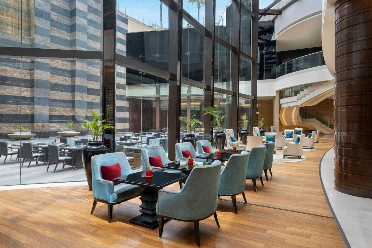 a restaurant with tables and chairs in a building at Bengaluru Marriott Hotel Whitefield in Bengaluru