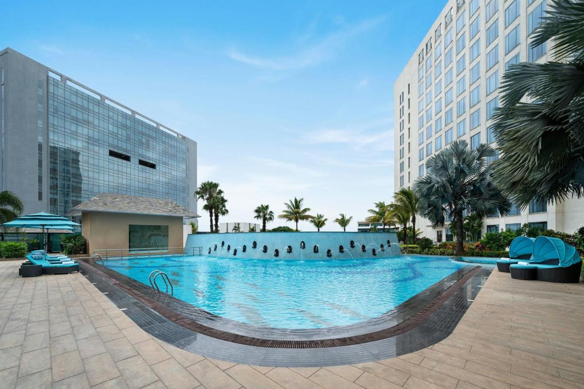 a large swimming pool with people standing in the water at Bengaluru Marriott Hotel Whitefield in Bengaluru