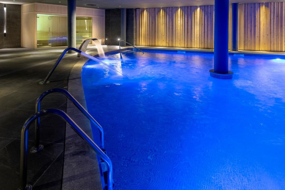 Una gran piscina con agua azul en un edificio. en Gran Hotel Rey Don Jaime, en Castelldefels