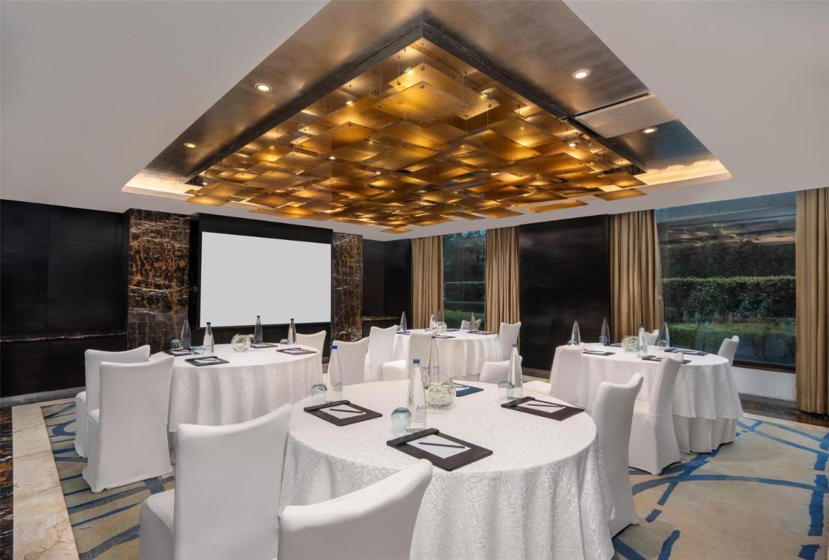 a conference room with white tables and white chairs at Radisson Blu Plaza Delhi Airport in New Delhi a conference room with white tables and white chairs at Radisson Blu Plaza Delhi Airport in New Delhi