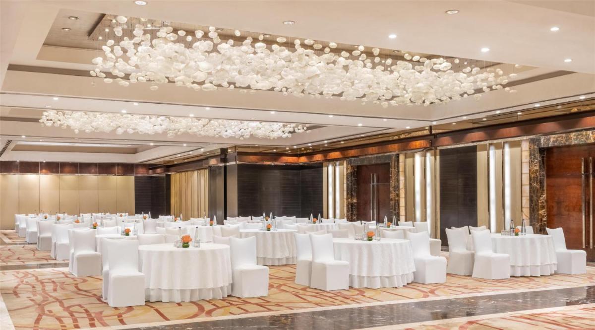 a banquet hall with white tables and white chairs at Radisson Blu Plaza Delhi Airport in New Delhi a banquet hall with white tables and white chairs at Radisson Blu Plaza Delhi Airport in New Delhi