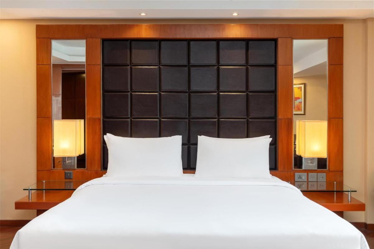 a bedroom with a large white bed with two pillows at Radisson Blu Plaza Delhi Airport in New Delhi a bedroom with a large white bed with two pillows at Radisson Blu Plaza Delhi Airport in New Delhi