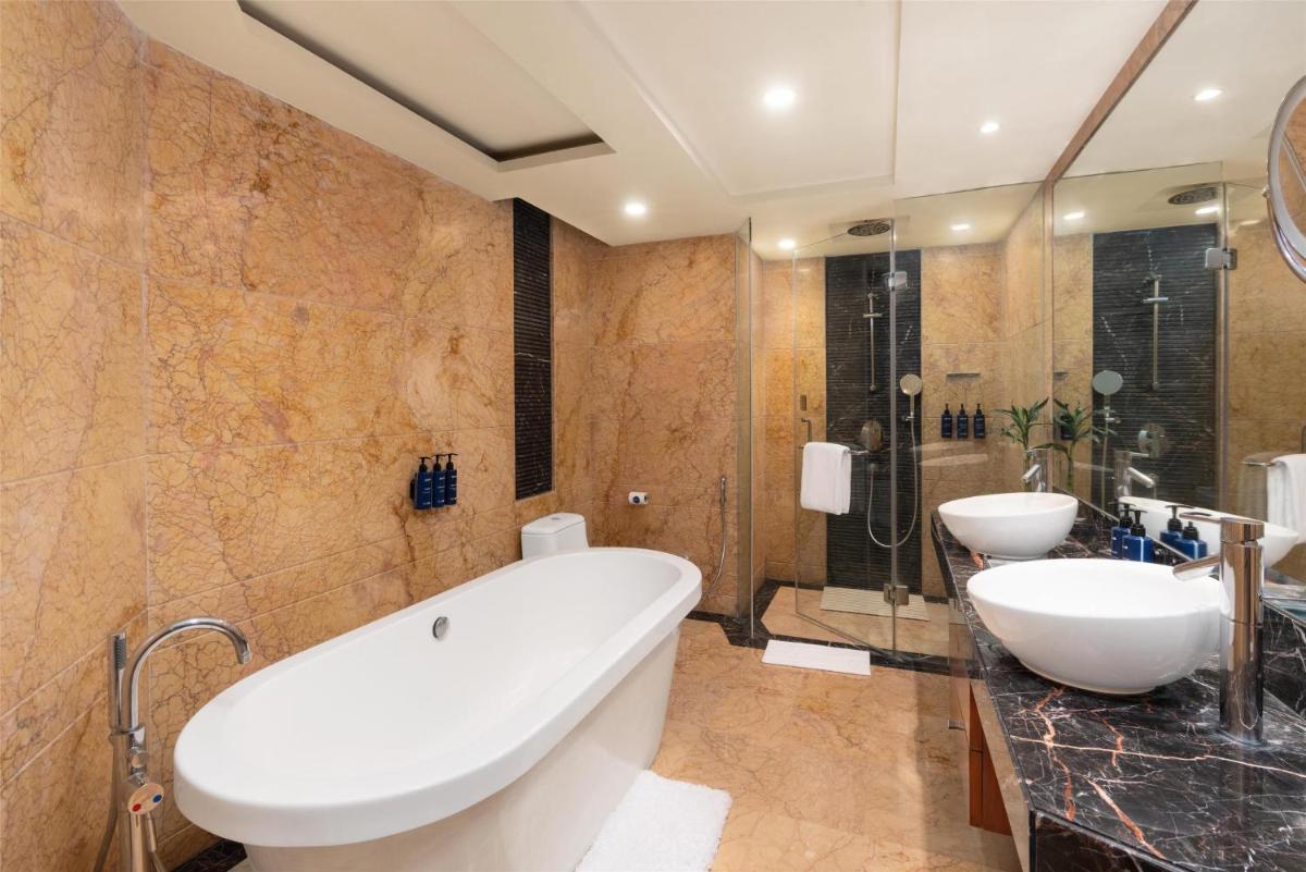 a bathroom with two sinks and a tub and a shower at Radisson Blu Plaza Delhi Airport in New Delhi a bathroom with two sinks and a tub and a shower at Radisson Blu Plaza Delhi Airport in New Delhi