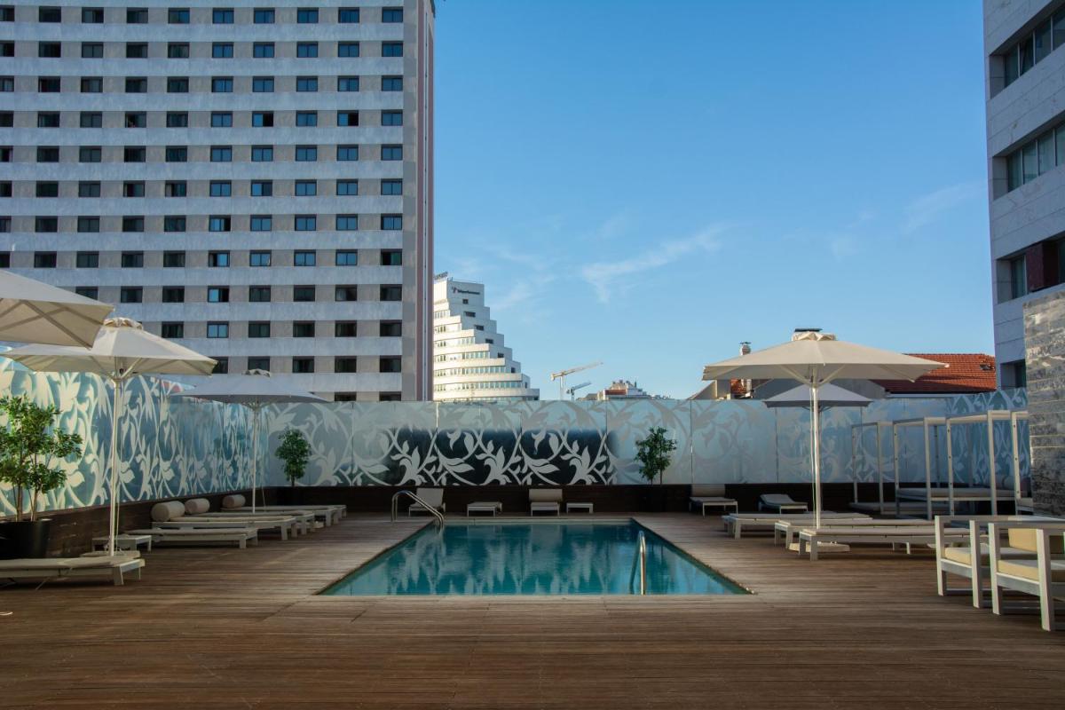 uma piscina no telhado de um edifício com guarda-sóis em VIP Grand Lisboa Hotel & Spa em Lisboa