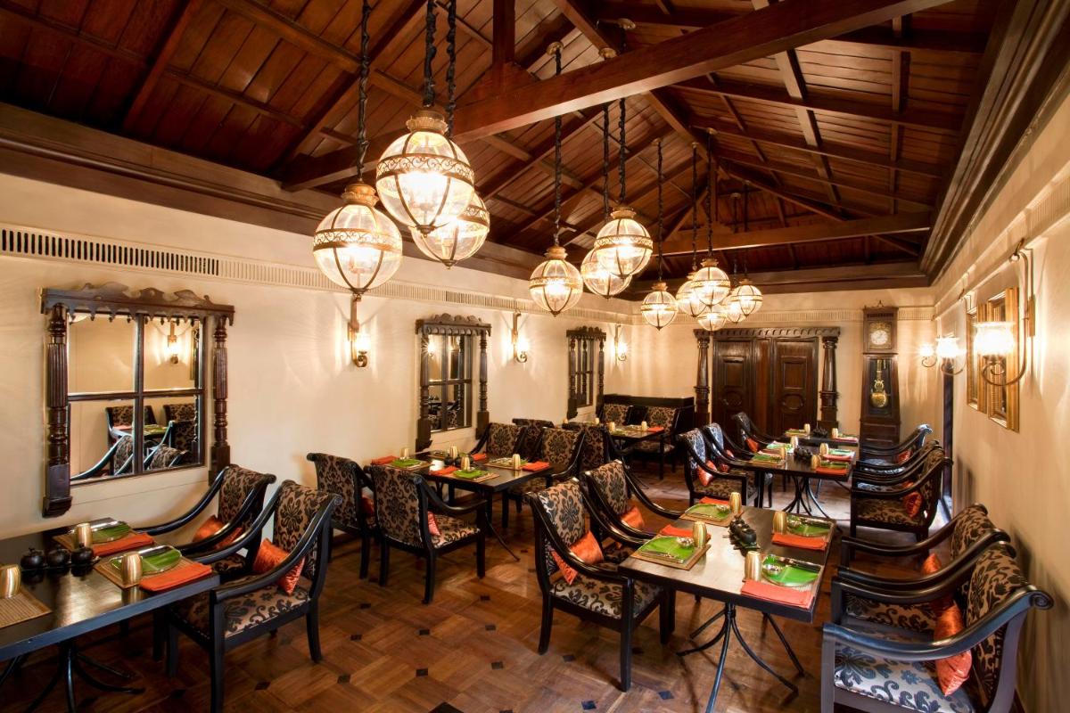 a dining room with tables and chairs and chandeliers at Vivanta Bengaluru Residency Road in Bengaluru a dining room with tables and chairs and chandeliers at Vivanta Bengaluru Residency Road in Bengaluru
