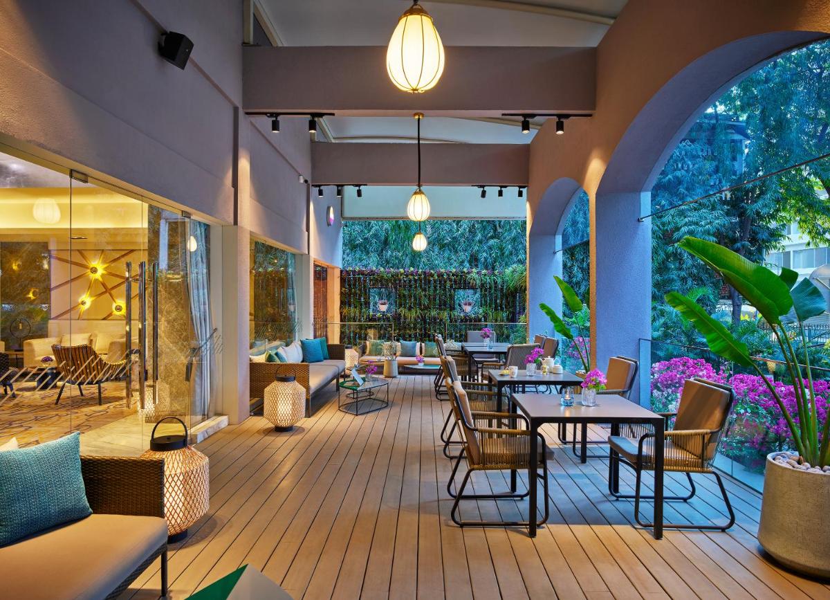 a restaurant with tables and chairs on a wooden deck at Vivanta Bengaluru Residency Road in Bengaluru a restaurant with tables and chairs on a wooden deck at Vivanta Bengaluru Residency Road in Bengaluru