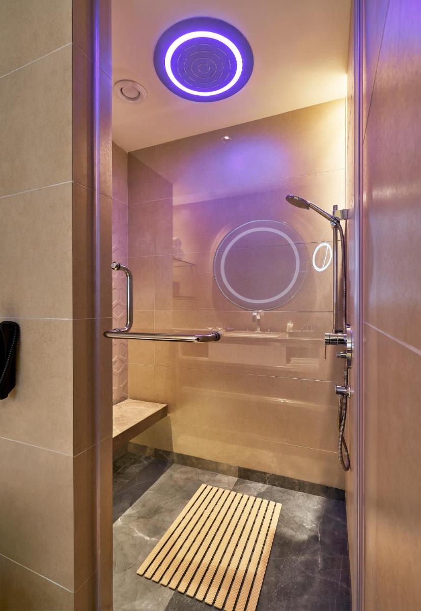 a bathroom with a shower with a sink and a mirror at Vivanta Bengaluru Residency Road in Bengaluru a bathroom with a shower with a sink and a mirror at Vivanta Bengaluru Residency Road in Bengaluru