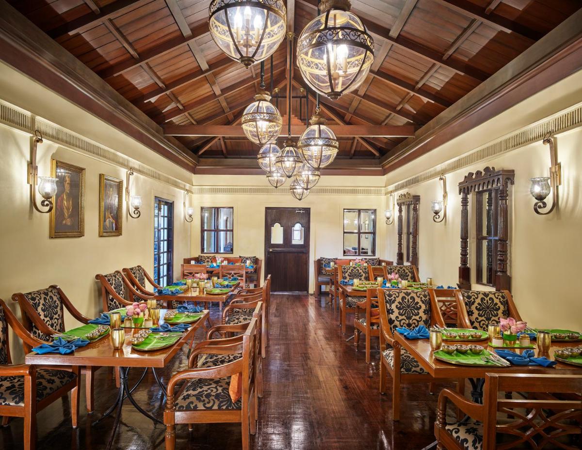 a restaurant with wooden tables and chairs and chandeliers at Vivanta Bengaluru Residency Road in Bengaluru a restaurant with wooden tables and chairs and chandeliers at Vivanta Bengaluru Residency Road in Bengaluru