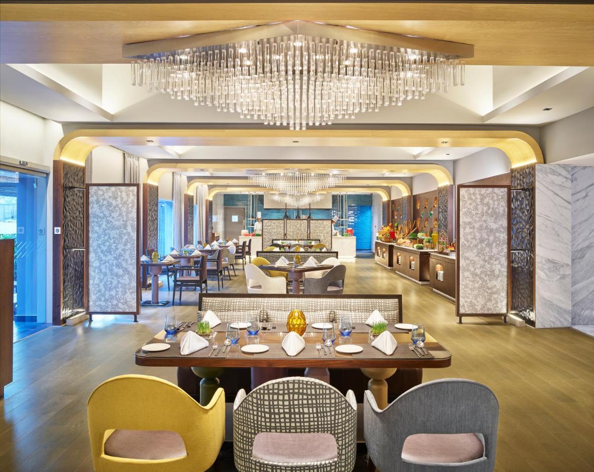 a dining room with a chandelier at Vivanta Bengaluru Residency Road in Bengaluru a dining room with a chandelier at Vivanta Bengaluru Residency Road in Bengaluru