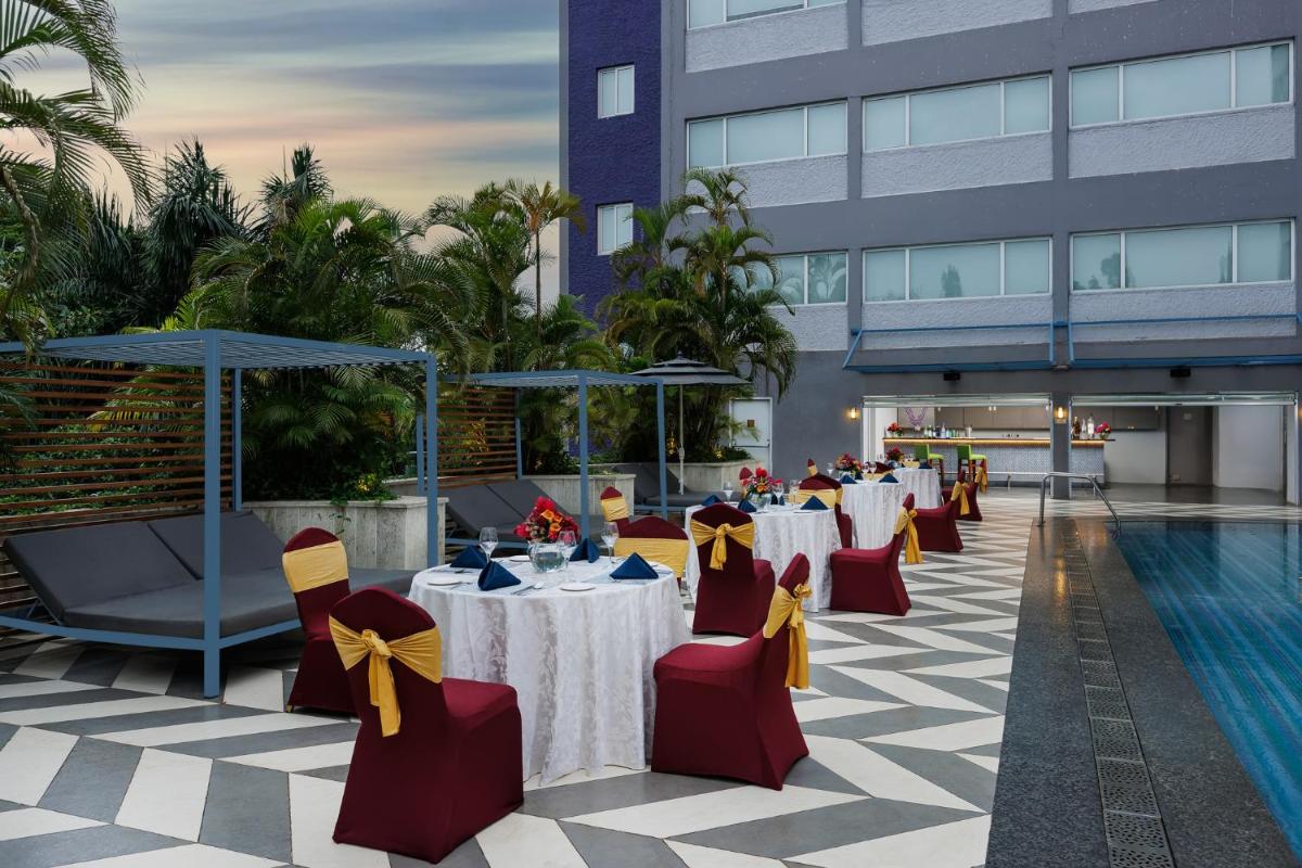 a hotel patio with tables and chairs and a pool at Vivanta Bengaluru Residency Road in Bengaluru a hotel patio with tables and chairs and a pool at Vivanta Bengaluru Residency Road in Bengaluru