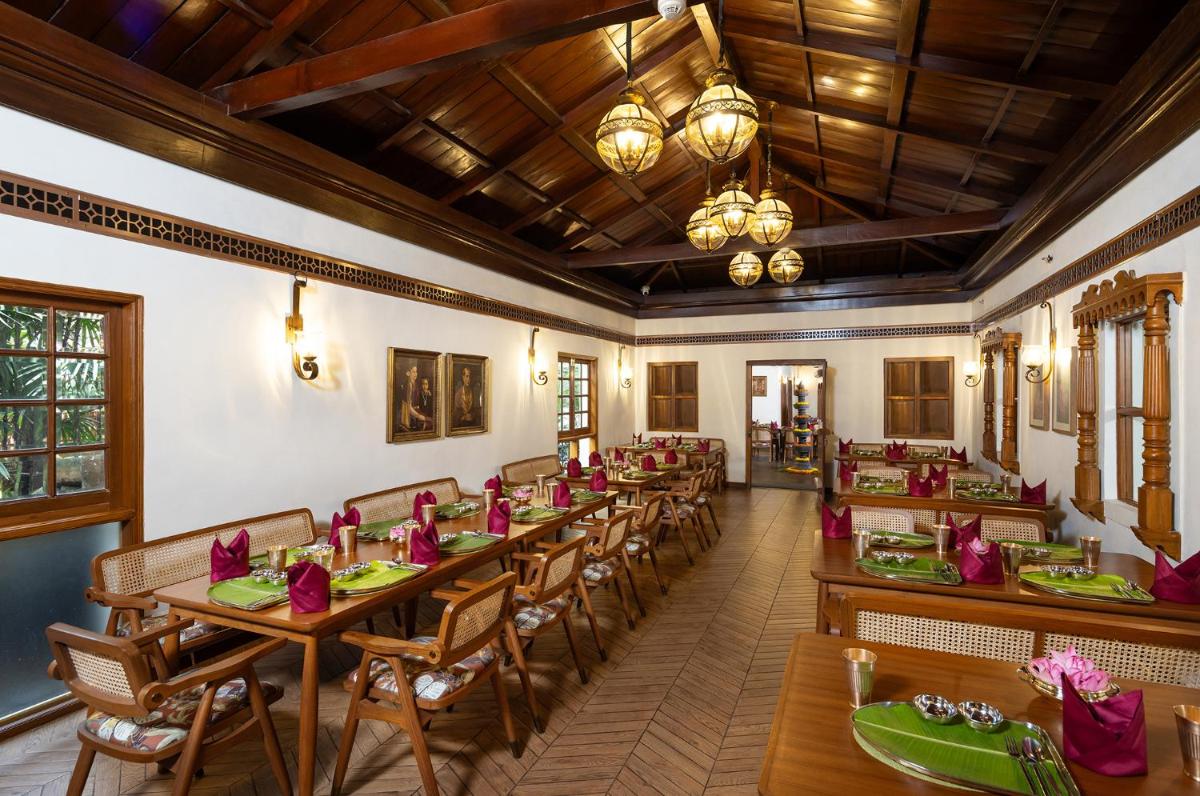 a dining room with wooden tables and chairs at Vivanta Bengaluru Residency Road in Bengaluru a dining room with wooden tables and chairs at Vivanta Bengaluru Residency Road in Bengaluru