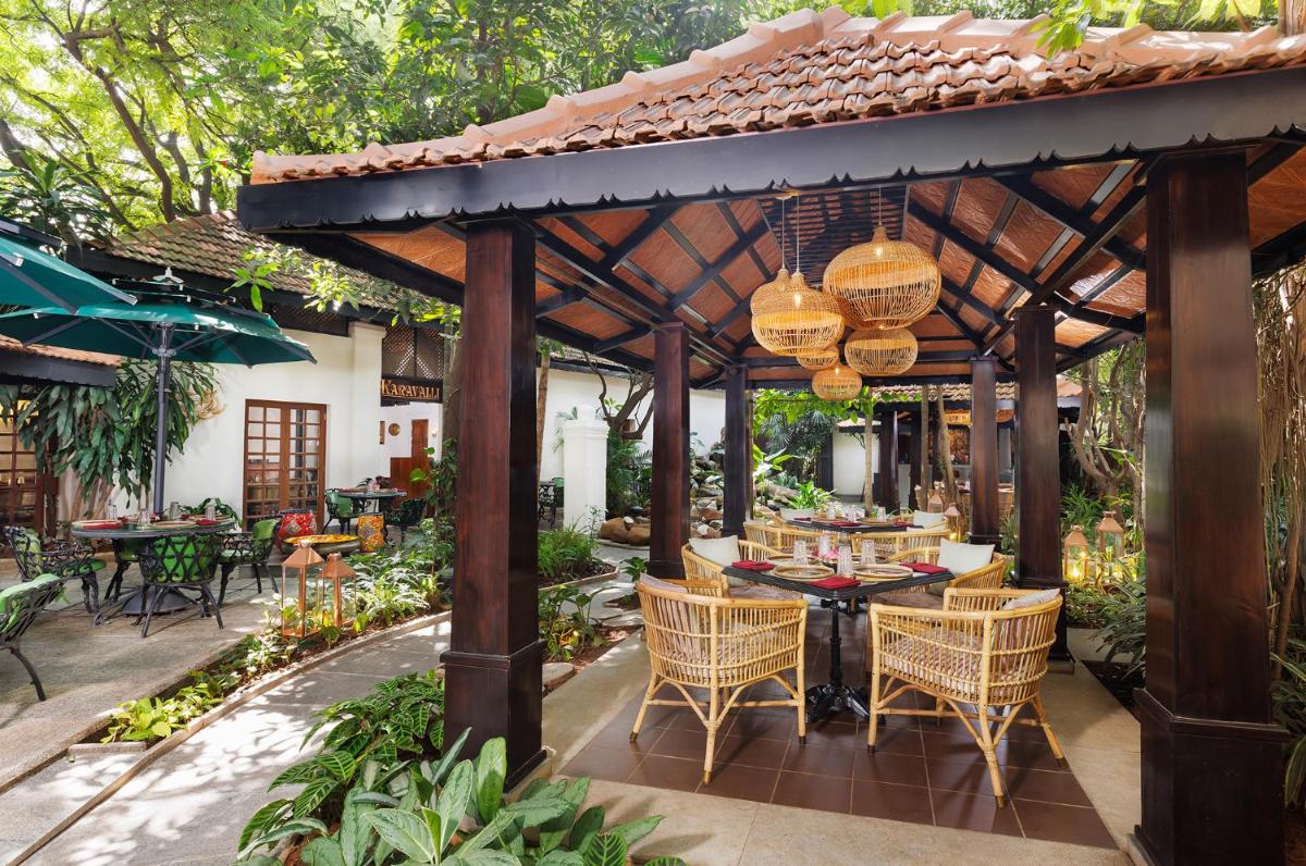 an outdoor dining area with a wooden pergola at Vivanta Bengaluru Residency Road in Bengaluru an outdoor dining area with a wooden pergola at Vivanta Bengaluru Residency Road in Bengaluru