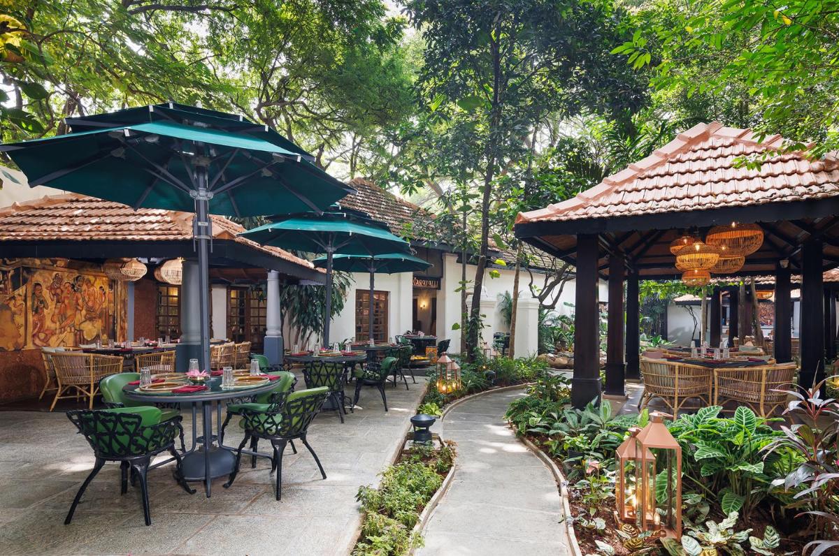 an outdoor patio with tables and chairs and umbrellas at Vivanta Bengaluru Residency Road in Bengaluru an outdoor patio with tables and chairs and umbrellas at Vivanta Bengaluru Residency Road in Bengaluru