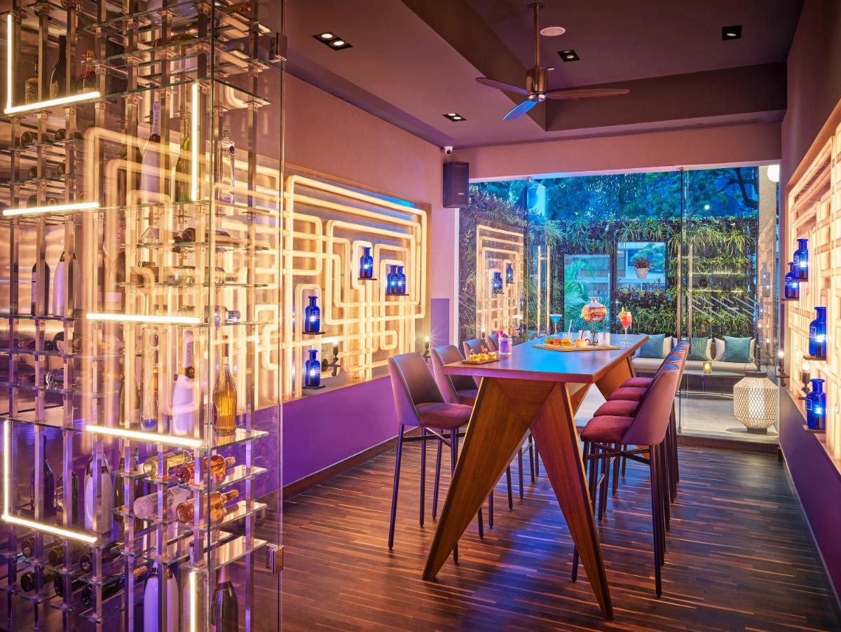 a dining room with a table and chairs and a wall of wine bottles at Vivanta Bengaluru Residency Road in Bengaluru a dining room with a table and chairs and a wall of wine bottles at Vivanta Bengaluru Residency Road in Bengaluru