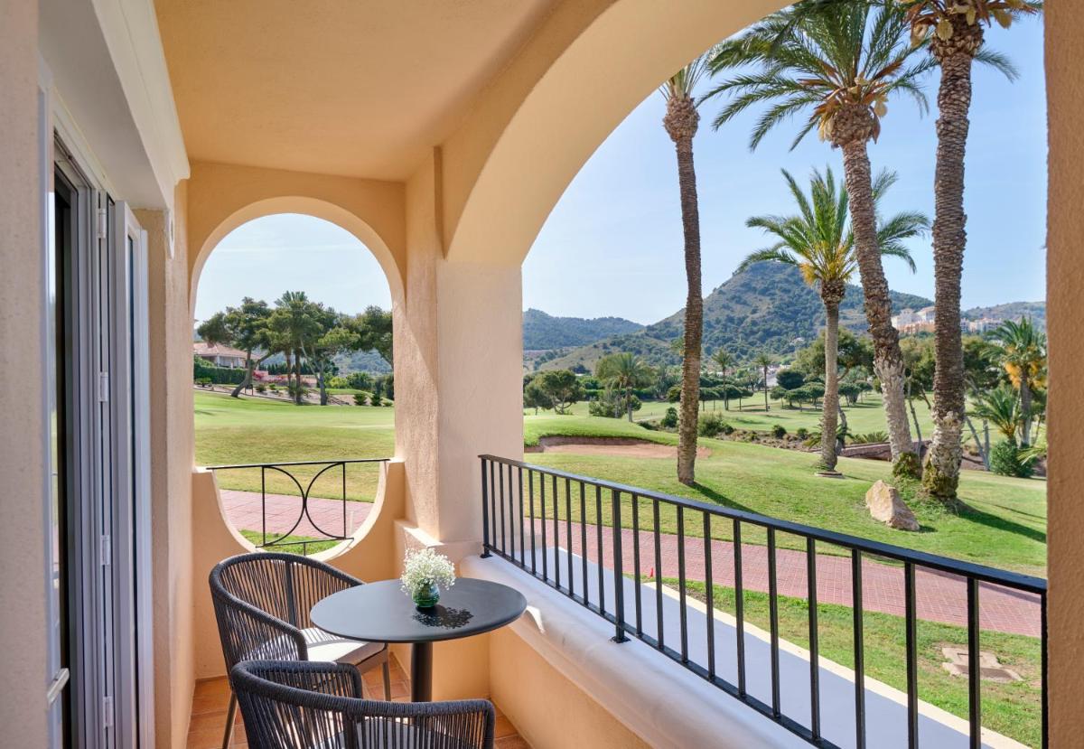 Un balcón con mesa y sillas y palmeras. en Grand Hyatt La Manga Club Golf & Spa, en La Manga del Mar Menor