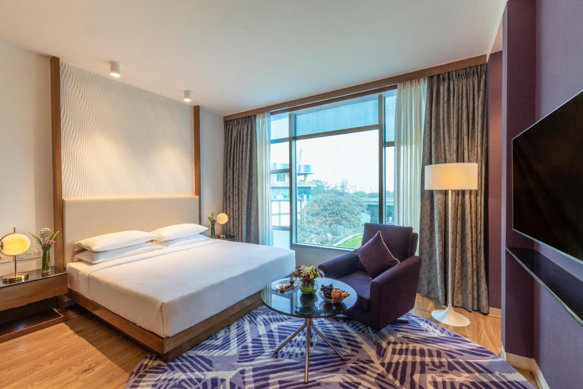 a hotel room with a bed and a large window at Vivanta Bengaluru, Whitefield in Bengaluru