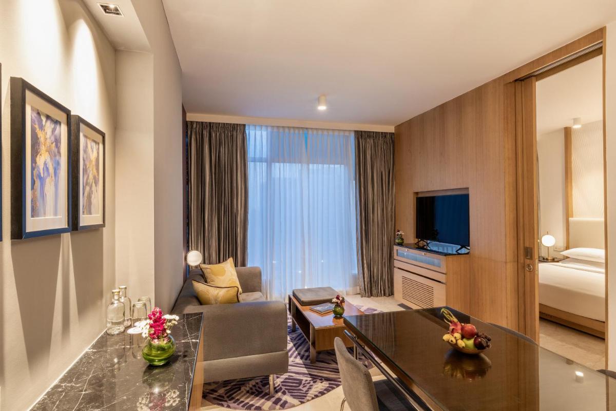a hotel room with a desk and a living room at Vivanta Bengaluru, Whitefield in Bengaluru