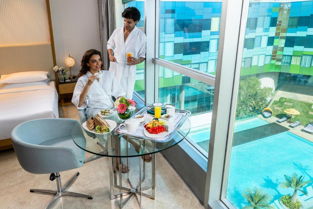 a man and woman in a hotel room with a table with food at Vivanta Bengaluru, Whitefield in Bengaluru