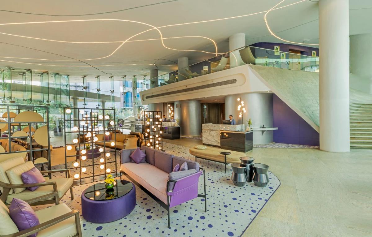 a lobby with purple furniture and a staircase at Vivanta Bengaluru, Whitefield in Bengaluru