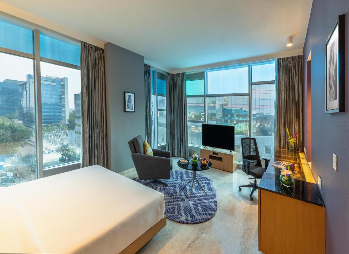 a hotel room with a bed and a desk and chairs at Vivanta Bengaluru, Whitefield in Bengaluru